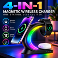 A 4-in-1 magnetic wireless charging stand shown with a smartphone, smartwatch, and white earbud case on a desk. The stand has a glowing rainbow LED ring and is set against a blurred home office background.